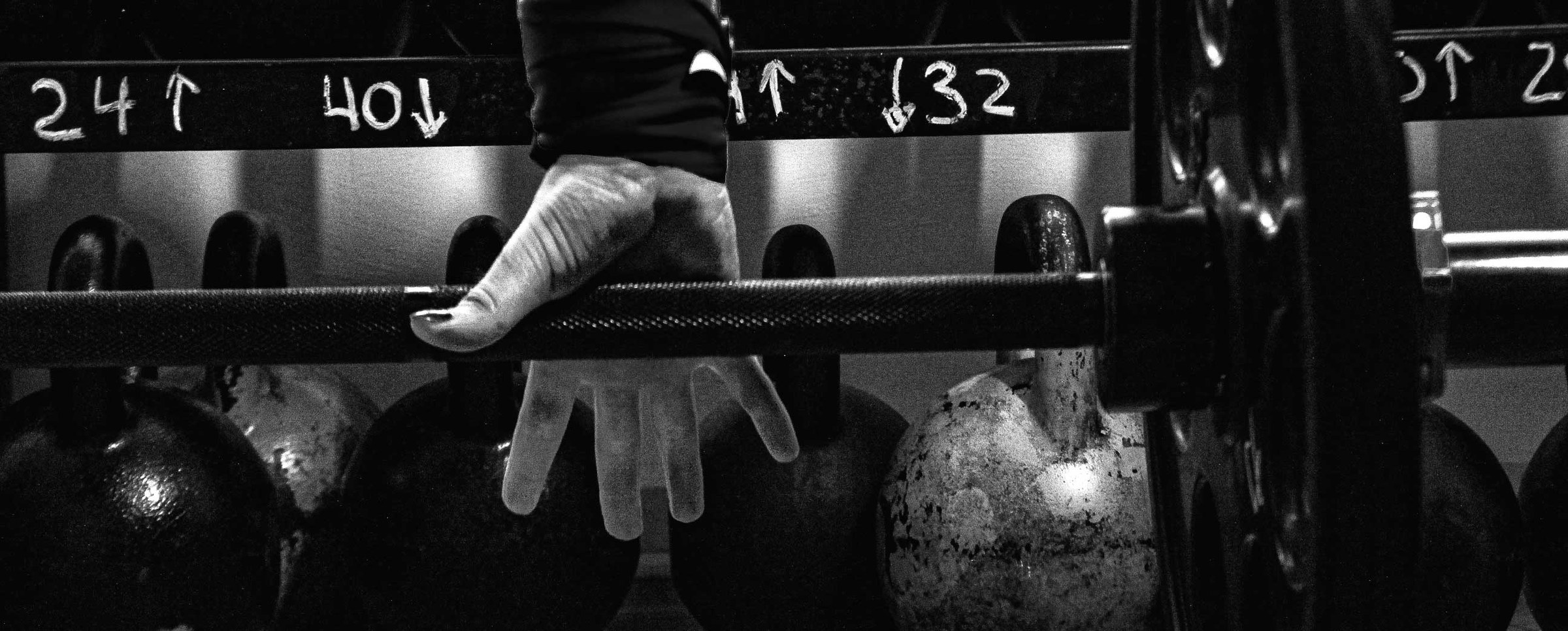 Hands gripping a loaded barbell on the floor